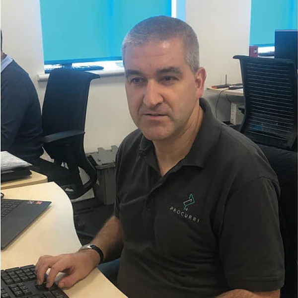 A headshot a man wearing a polo shirt with the Procurri logo on.
